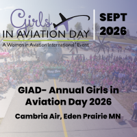 Crowd gathered on a runway for Girls in Aviation Day 2026, with planes in the background and bold event text overlaid (SEPT 2026).